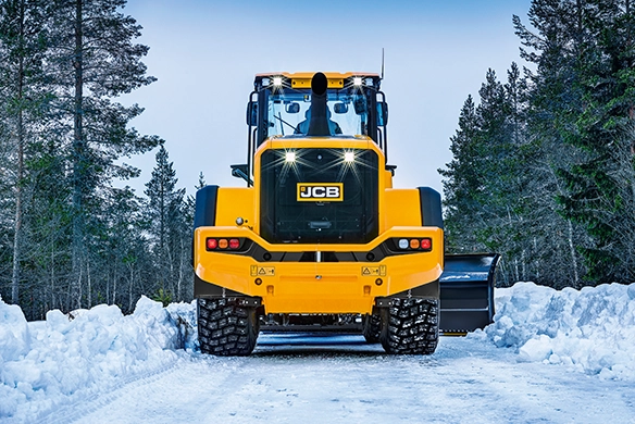 Rear view of JCB 457S wheel loader operating in snowy conditions with heavy-duty tyres and snow attachment