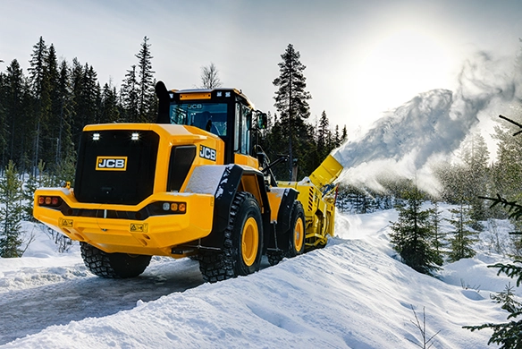 JCB 457S wheel loader clearing snow in a forest environment using a high-capacity snow attachment