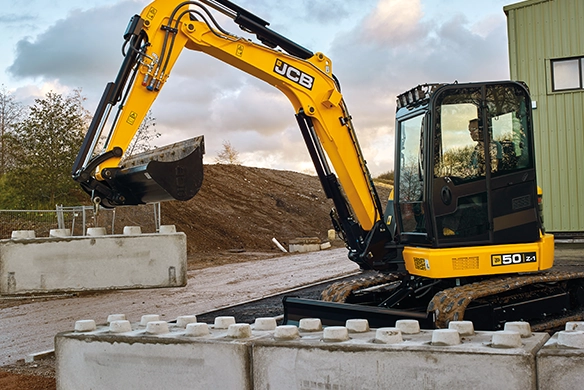 JCB 50Z-1 mini excavator working between concrete blocks on a job site