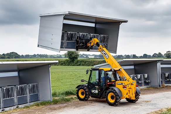 JCB 525-60 telescopic handler lifting livestock equipment at a modern agricultural building