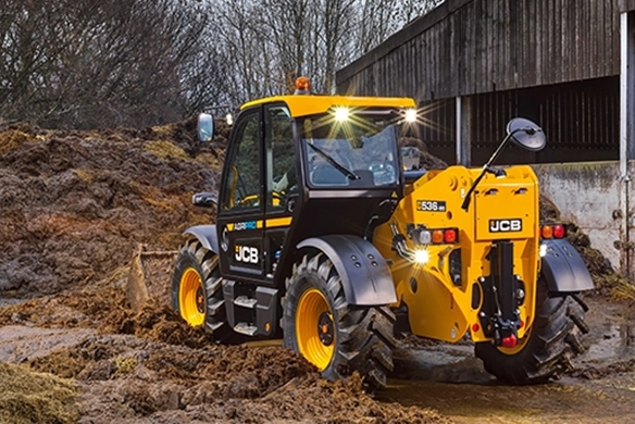 JCB 536-95 telescopic handler operating on a farm with rear view in muddy conditions