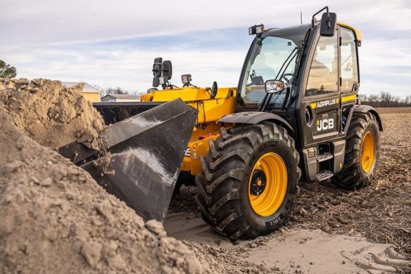 JCB 542-70 telescopic handler pushing a mound of loose soil with a front bucket on a site
