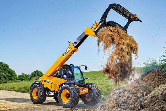 JCB 542-70 telescopic handler tipping silage from a grapple bucket onto a pile in an open field
