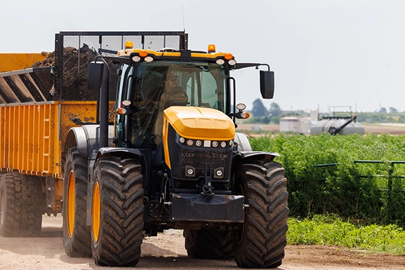 JCB 8000 Series tractor hauling a full dump trailer along a farm track