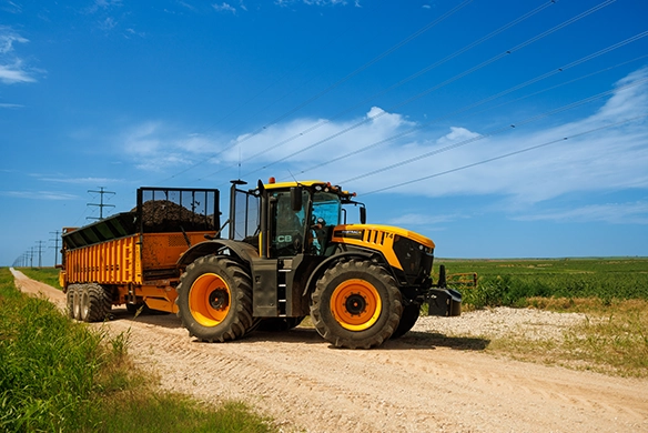 JCB 8000 Series tractor towing a loaded trailer on a rural gravel road