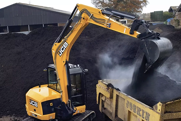 JCB 90Z-2 mini excavator loading material into a trailer at an industrial site