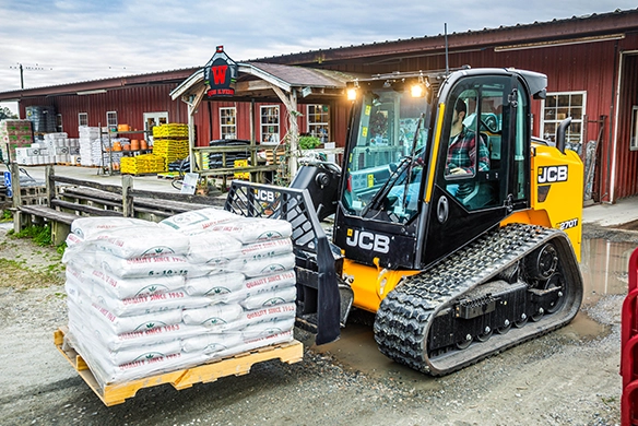 JCB 270T compact track loader transporting bagged materials at an agricultural supply yard
