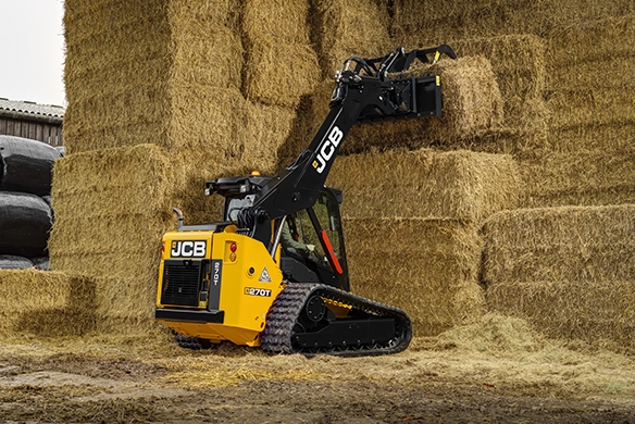 JCB 270T compact track loader stacking hay bales inside a barn