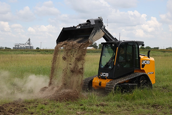 JCB 270T compact track loader dumping soil during land preparation work