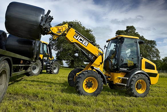 JCB TM220 telescopic wheel loader handling wrapped silage bales in a field