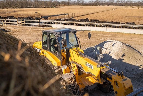 JCB TM320 telescopic wheel loader handling material near livestock housing