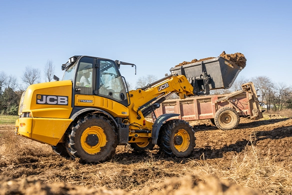JCB TM320 telescopic wheel loader loading material onto a trailer on an agricultural site