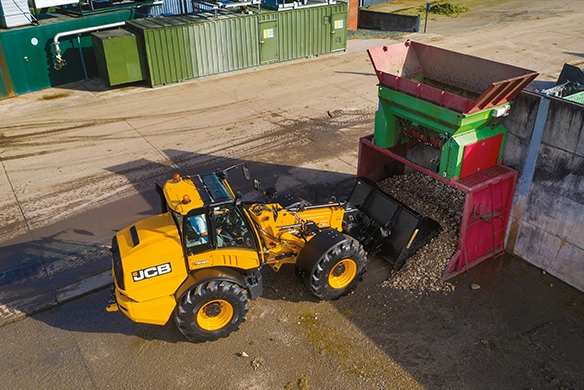 JCB TM420 telescopic wheel loader feeding processed material into an industrial hopper