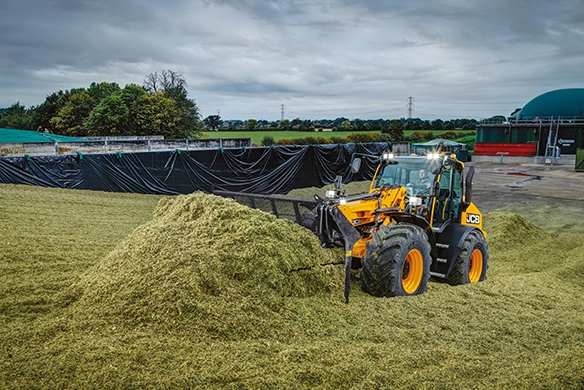 JCB TM420 telescopic wheel loader pushing silage material at an agricultural processing site
