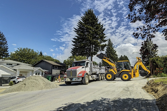 JCB 4CX PRO backhoe loader loading material into a truck during roadworks