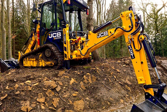 JCB 1CXT compact track backhoe loader excavating material on a sloped off-road site