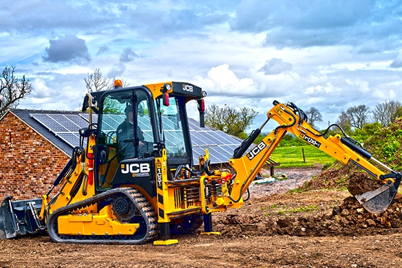 JCB 1CXT compact track backhoe loader trenching on a rural construction site