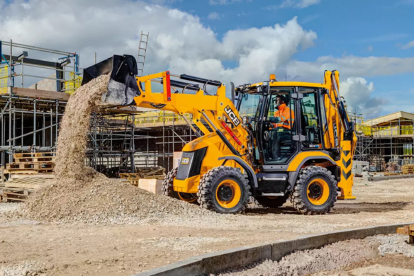 JCB 3CX compact backhoe loader dumping material on an active construction site