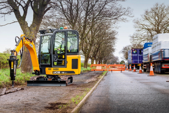 JCB 19C-1 mini excavator working roadside with traffic management and safety barriers