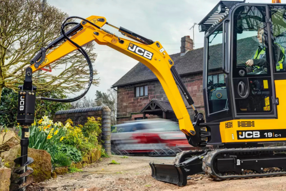 JCB 19C-1 mini excavator drilling with auger attachment beside residential driveway