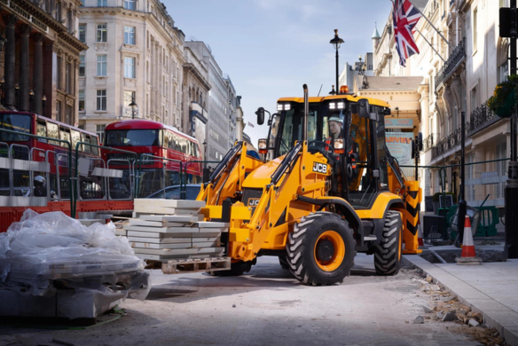 JCB 3CX compact backhoe loader transporting materials during city street construction